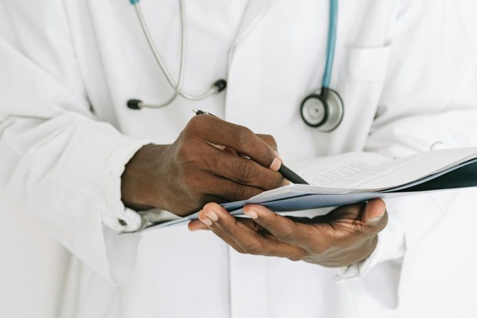 torso de um médico de bata com estetoscópio ao pescoço